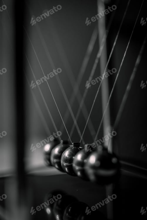 Preview: Greyscale shot of Newton's cradle under the lights with a blurry background