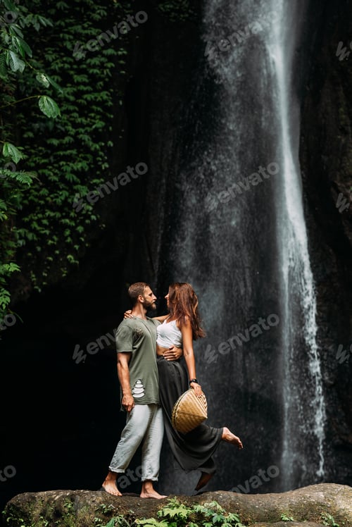 Preview: A man embraces a woman at a waterfall. A couple in love at a waterfall. Honeymoon trip