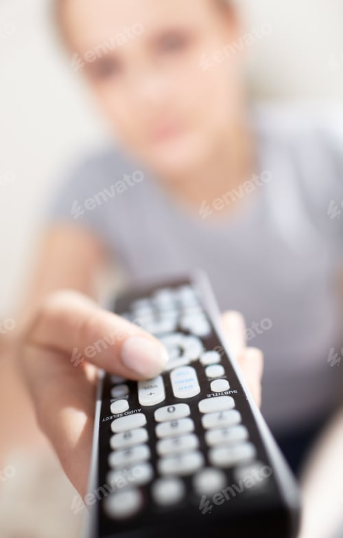 Preview: Young woman with remote watching TV