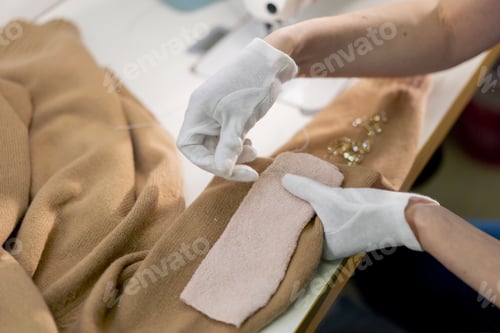 Preview: close up professional dry cleaner young girl manually hems missing beads on a jacket