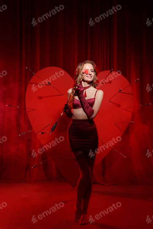 Preview: Smiling woman in red lingerie with broken heart and arrows on red stage