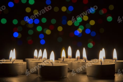 Preview: Tiny candles igniting together in the dark with lights shining in the background