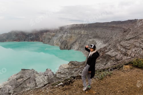 Preview: Woman tourist looks at the sulphur lake on the Ijen volcano on the island Java