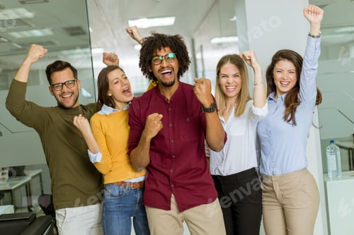 Preview: Group of young excited business people with hands up standing in office