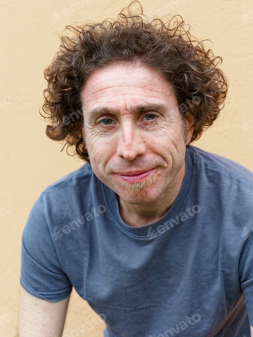 Preview: Man with curly hair smiling at the camera.