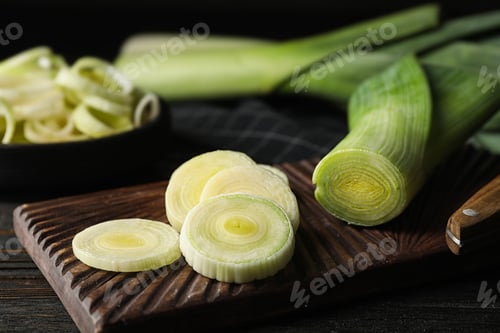 Preview: Fresh raw leeks on black wooden table. Closeup view of ripe onion