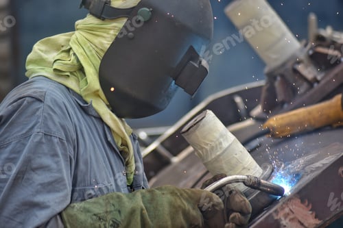 Preview: Unrecognizable industrial steel worker wearing protective welding gear at work