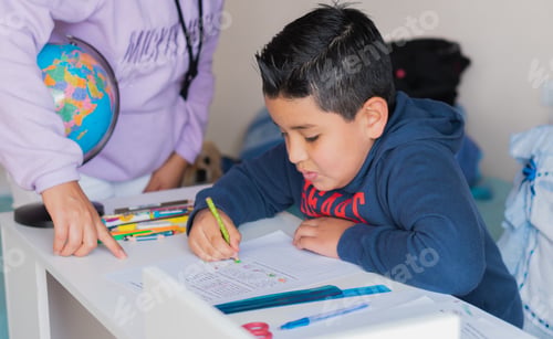 Preview: High angle shot of a Hispanic child receiving classes from his teacher at home.