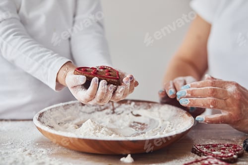 Preview: Close up view of woman with her granddaughter preparing food with flour on kitchen