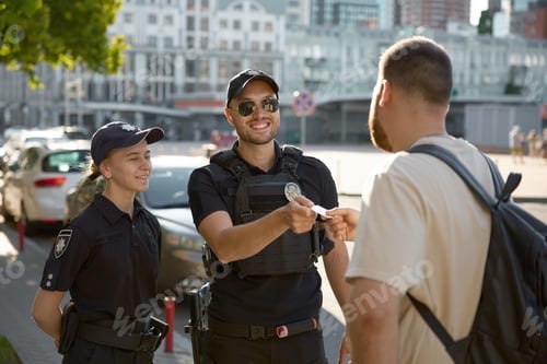 Preview: Friendly smiling patrol policeman giving back passport to citizen