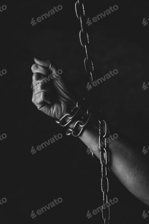 Preview: Hand of a person chained on black background, feeling a lack of freedom, prison