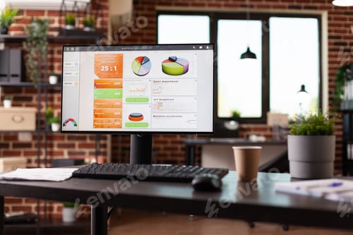 Preview: Computer with business charts on desk in empty workplace