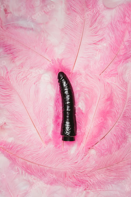 Preview: Black dildo toy on pink feathers