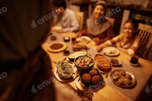 Vista previa: Close up of Middle Eastern woman serving food for dinner to her family.