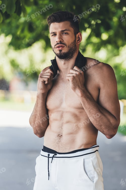 Preview: young handsome shirtless sportsman resting after workout with towel on neck