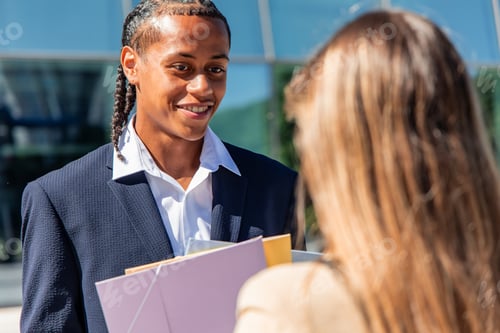 Preview: multicultural businessman holding folders smiling at his female colleague in the financial district
