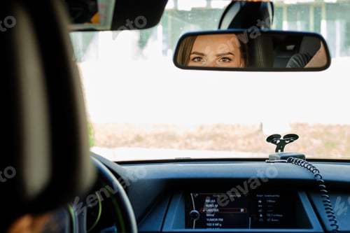Preview: Reflection of female eyes in rearview mirror of a car