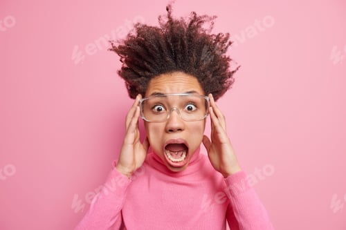 Preview: Mad shocked woman sceams loudly stares in terror keeps mouth wide opened has hair standing up wears