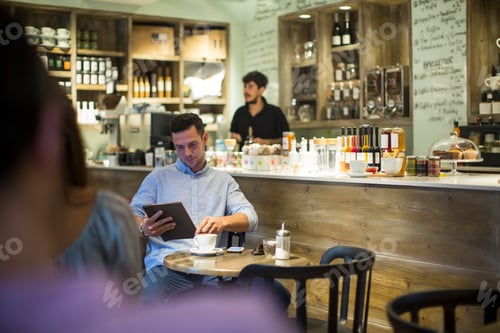 Preview: Man sitting in cafe browsing digital tablet