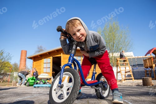 Preview: Little cute adorable caucasian toddler boy portrait having fun riding exercise balance run bike push