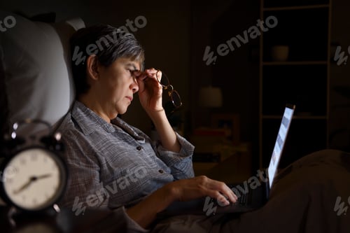 Preview: Senior woman using laptop at night