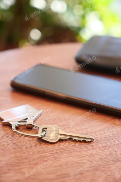 Preview: A smartphone along with keys placed on a beautifully crafted wooden table surface