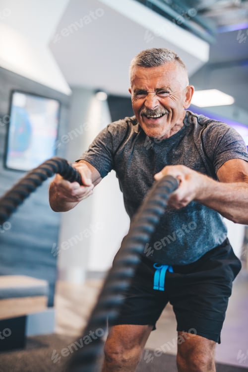 Preview: Senior man exercising with ropes at the gym.