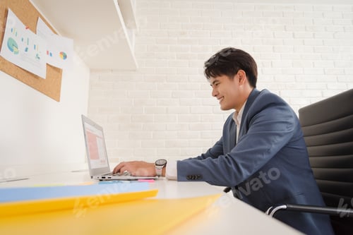 Preview: Young business Asian man working on his laptop with smile and confidence in modern workplace office.