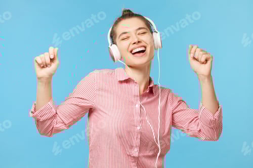 Preview: Young smiling dancing girl wearing eyeglasses and shirt, listening to music through headphones
