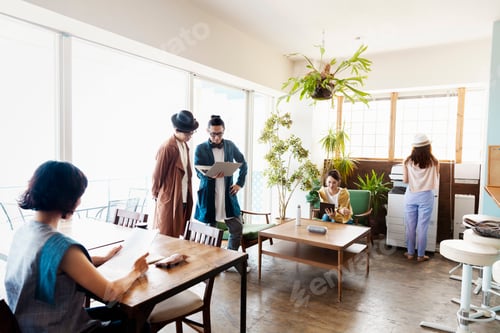 Preview: Group of young Japanese professionals working on laptop computers in a co-working space.