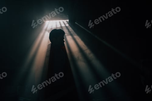 Preview: A man silhouetted against a window with sunshine pouring through in a dark room