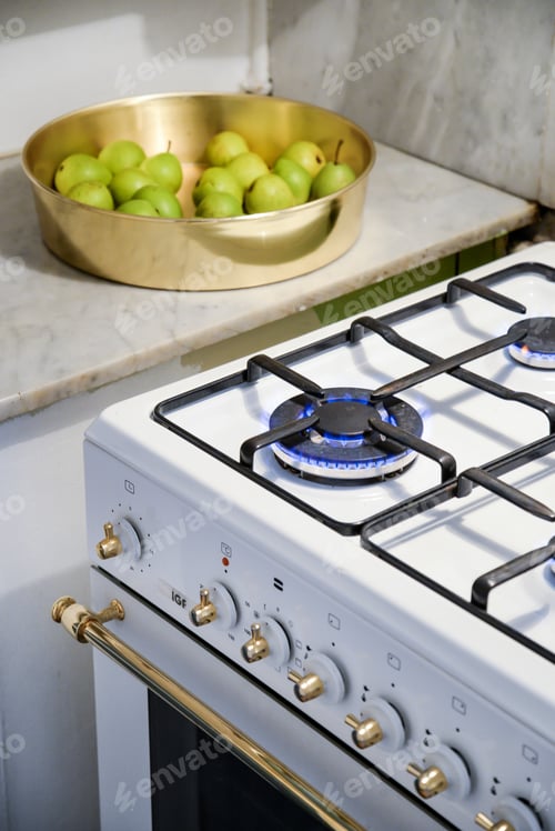 Preview: Vertical high angle shot of a burning stove and a bowl with pears in the kitchen