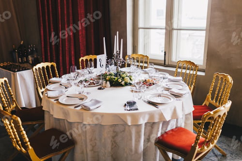 Preview: Round table with many chairs around served for many people in retro style with white tablecloth