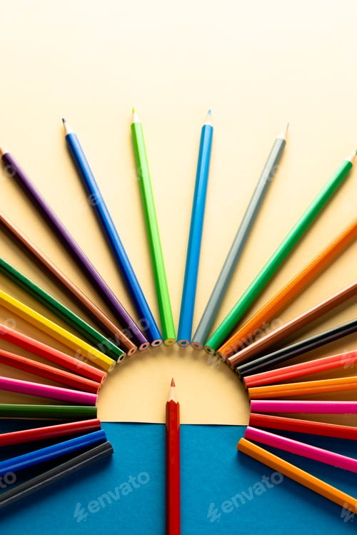 Preview: Close up of multi coloured pencils in circle and copy space on blue and yellow background