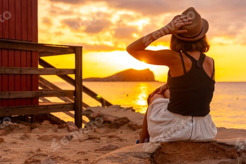 Preview: Woman with hat at sunset in Cala Comte beach on the island of Ibiza. Balearic