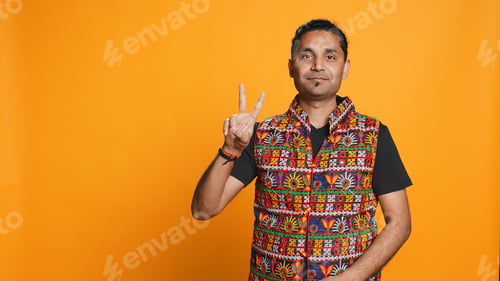 Preview: Portrait of man crossing fingers and doing victory sign, studio background