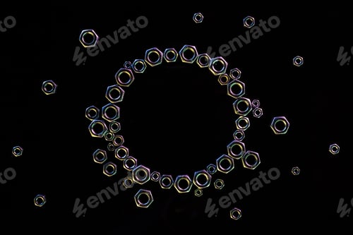 Preview: top view of circle of scattered metal nuts isolated on black