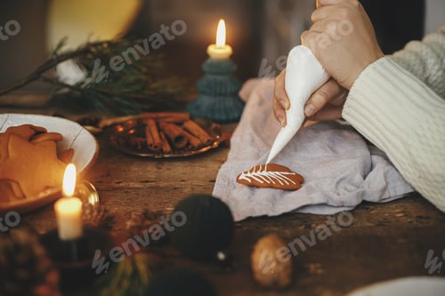 Preview: Hands decorating gingerbread cookie christmas tree with frosting on rustic table. Atmospheric image