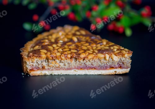 Preview: Selective focus shot of a sliced pie with nuts on a black surface