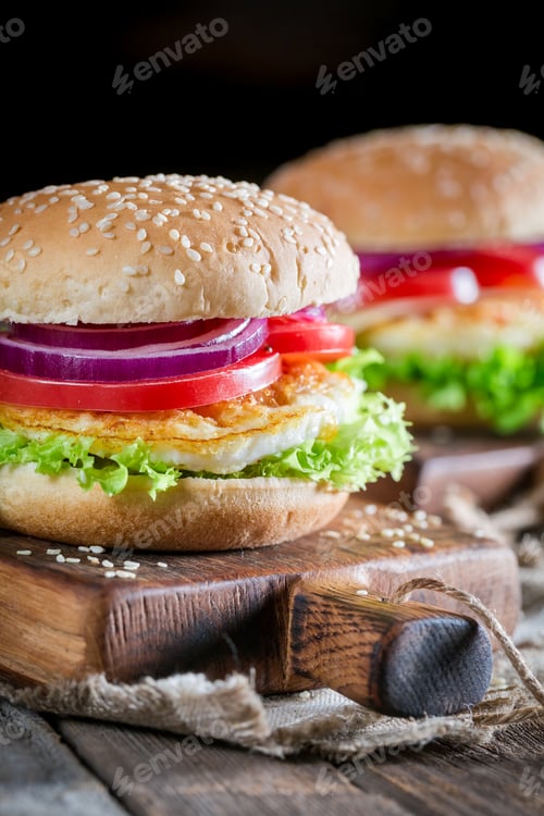 Preview: Closeup of two burgers with vegetables and fried egg