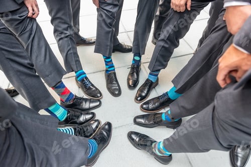 Preview: High angle shot of the groomsmen standing in a circle and showing their colorful socks