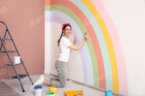 Preview: Young woman painting rainbow on white wall indoors