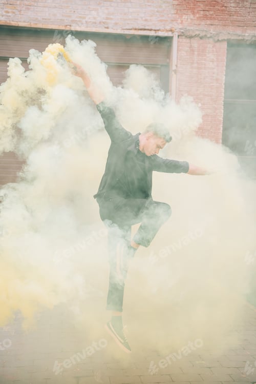 Preview: young male contemporary dancer jumping in smoke on urban street