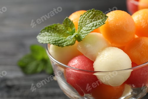 Preview: Melon and watermelon balls with mint in dessert bowl on table, closeup