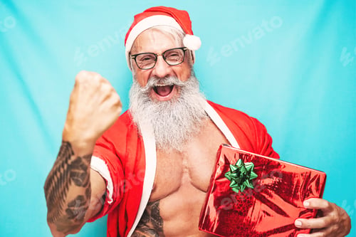 Preview: Happy fit Santa Claus holding Christmas present