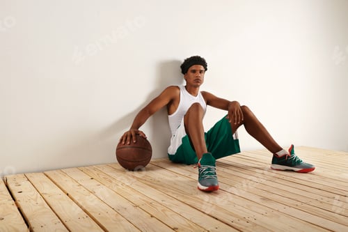 Preview: Handsome young black basketball player sitting on the wooden floor