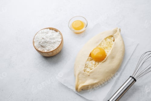 Preview: Uncooked khachapuri with egg yolk and whisk on white background