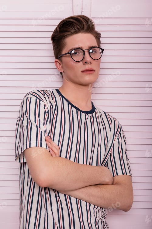 Preview: Stylish young man in fashion glasses with a hairstyle in a trendy striped t-shirt. Trendy fashion.