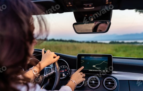 Preview: Girl putting in the address in the car navigation system while driving through countryside