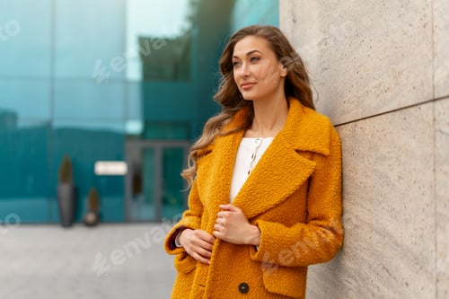 Preview: Business woman standing near corporative building outdoor dressed yellow stylish coat